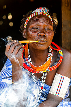 Woman with beauty scars from the Toposa tribe smoking a pipe, Eastern Equatoria, South Sudan, Africa