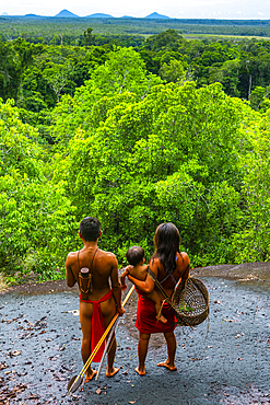 Couple with their child, standing on a giant rock, Yanomami tribe, southern Venezuela, South America