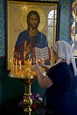 Woman lighting candles at a Russian Orthodox church service in Volgograd, Russia, Europe