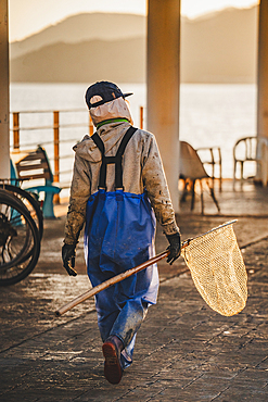 A female fisherman in Peng Chau in Hong Kong with a net at sunset