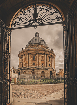 A vertical image of the Radcliffe Camera and Radcliffe Square framed by a metal gate in Oxford