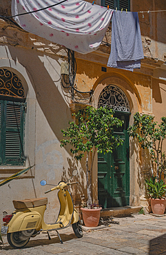 Corfu Old Town and black Vespa motorbike with hanging laundry.