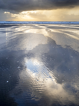 Rain clouds and reflections on Rhossili beach at sunset showing the shipwreck of the Helvetia, Rhossili, Gower, South Wales, United Kingdom, Europe