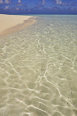 Pristine shallow waters lap against the white coral sand of a tropical beach; Havodda Island, in the far south of the Maldives, Gaafu Dhaalu atoll, Indian Ocean.