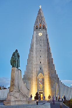 A dusk view of the spire of Hallgrimskirkja Church, fronted by a statue of Leifur Eriksson, founder of Iceland, in central Reykjavik, Iceland, Polar Regions