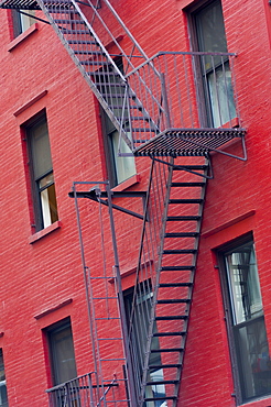 Red painted tenement block and fire escapes, New York, United States of America, North America