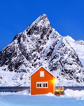 Yellow rorbuer hut in the snow at twilight, Sakrisoy, Moskenesoya, Lofoten Islands, Nordland, Norway, Europe