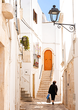 Woman walking in a narrow street in the Old Town, Locorotondu, Puglia, Italy, Europe