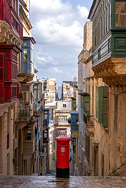 Street scene of alley with traditional homes, colourful balconies and a red post box, Valletta, Malta, Europe