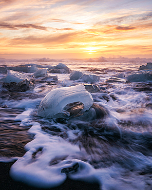 Glacier ice on Diamond Beach at sunrise with crashing waves, near Jokulsarlon, South Iceland, Iceland, Polar Regions