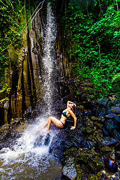 Woman posing for a picture under a waterfall at the Beji Guwang Hidden Canyon, Bali, Indonesia, Southeast Asia, Asia