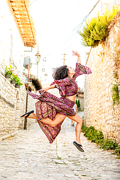 Woman jumping on the street in Berat, Albania, Europe