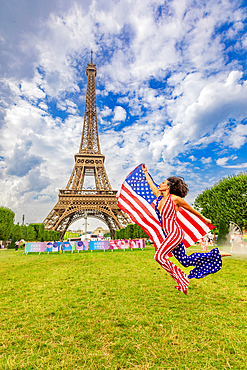 Patriotic American Woman jumping and cheering for Team USA and the Paris 2024 Olympics in front of the Eiffel Tower, Paris, France, Europe