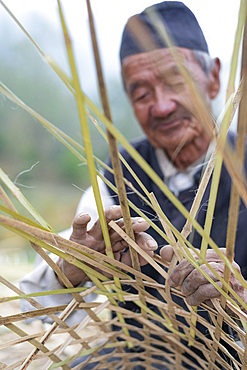 A old Nepali man makes a traditional basket by weaving bamboo, Kathmandu Valley, Nepal, Asia