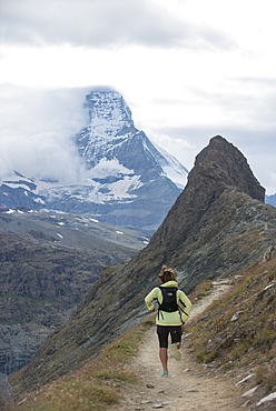 Running a trail in the Swiss Alps near Zermatt with a view of The Matterhorn in the distance, Zermatt, Valais, Switzerland, Europe