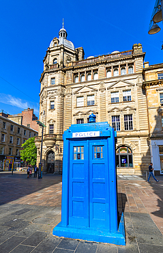 Blue police box stands in front of historic building on Buchanan Street in Glasgow during bright and sunny day