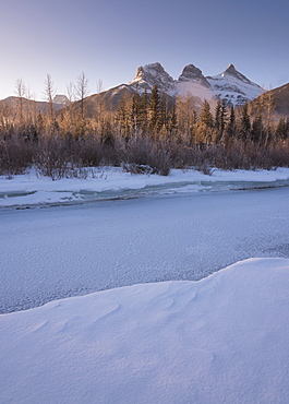 Winter sunrise with frozen Bow River and Three Sisters, Canmore, Alberta, Canadian Rockies, Canada, North America