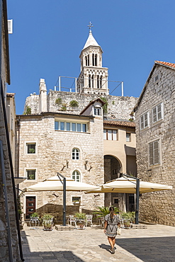 Woman walking in summer, with the bell tower of St. Domnius Cathedral in the background, Split, Split-Dalmatia county, Croatia, Europe