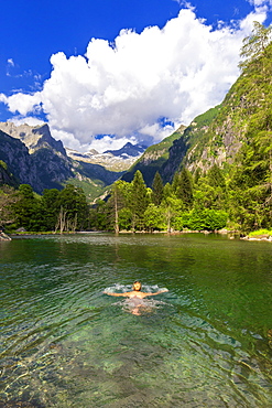 A girl swims in a clear alpine lake, Val di Mello (Mello Valley), Valmasino, Valtellina, Lombardy, Italy, Europe