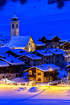 Church and houses illuminated during a winter twilight, Livigno, Valtellina, Lombardy, Italy, Europe