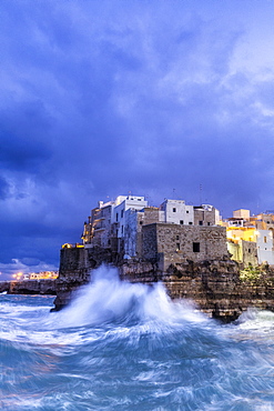 Waves crash on the cliff during a winter storm at dusk, Polignano a Mare, Apulia, Italy, Europe