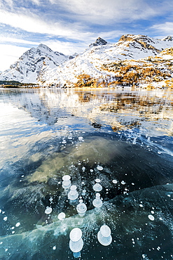 Methane bubbles in the icy surface of Silsersee with snowy peak, Lake Sils, Engadine Valley, Graubunden, Swiss Alps, Switzerland, Europe