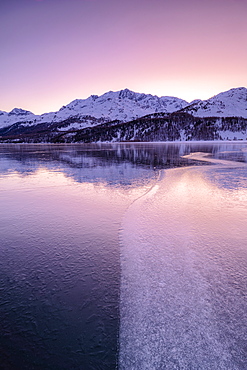 Colors of sunrise is reflected on the icy surface of Lake Sils, Engadine Valley, Graubunden, Swiss Alps, Switzerland, Europe