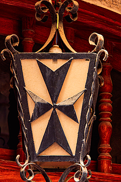 Traditional iron lamp lantern detail with Maltese cross design outside a city building, Malta, Mediterranean, Europe