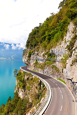 A curved road built into the side of a mountain next to Lake Thun, Interlaken, Bernese Oberland, Bern, Switzerland, Europe