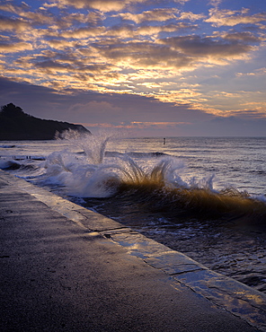 Waves backlit by the dawn sun reflect off the sea wall and impact with an incoming one, Exmouth, Devon, England, United Kingdom, Europe