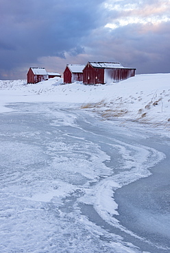 Fishermans houses and ice formations with dramatic sky in winter, Eggum, Lofoten Islands, Arctic, Norway, Europe