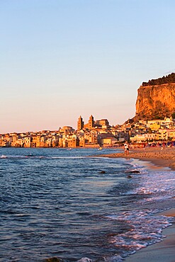 View from beach along water's edge to the town and UNESCO World Heritage Site listed Arab-Norman cathedral, sunset, Cefalu, Palermo, Sicily, Italy, Mediterranean, Europe