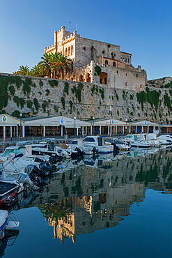 View across harbour at sunrise, the Town Hall reflected in calm water, Ciutadella (Ciudadela), Menorca, Balearic Islands, Spain, Mediterranean, Europe