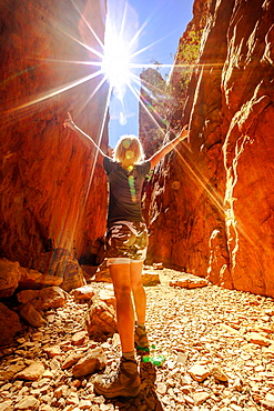 Carefree tourist woman enjoying the picturesque natural alleyway of Standley Chasm as mid-day sun rays hit spectacular gorge, West MacDonnell National Park, Outback Red Centre, Northern Territory, Australia, Pacific