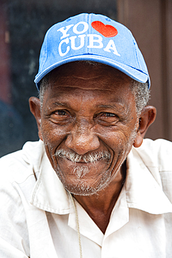 Local man wearing an I love Cuba hat relaxing on the street in Trinidad, Cuba, West Indies, Caribbean, Central America