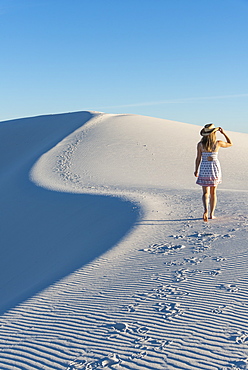 A woman walking along the S curve of a dune's ridge in White Sands National Park, New Mexico, United States of America, North America