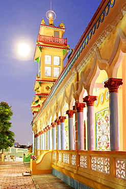 The Cao Dai temple in Vung Tau lit up at dusk with the full moon to the left of the tower, Vung Tau, Vietnam, Indochina, Southeast Asia, Asia