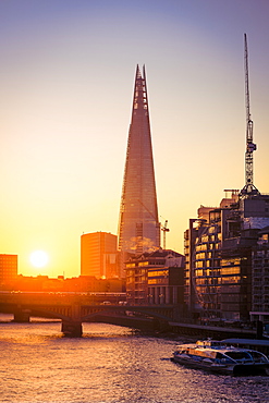 The Shard at sunrise on a cold winters morning with River Thames and river cruise boat and sun reflections in windows, London, England, United Kingdom, Europe