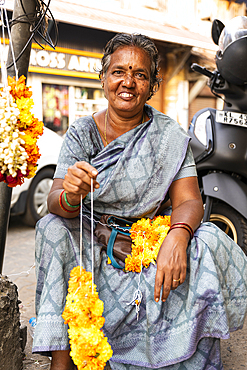 Portrait of a woman making yellow Varmala, flower garlands, Fort Kochi, Kerala, India