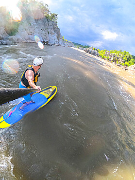 Skip Brown stand up paddle surfs a whitewater wave on the Potomac River as an afternoon thunderstorm moves in, Virginia, United States of America, North America