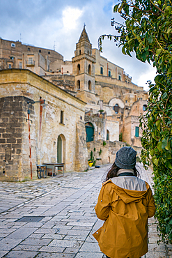 Backview of woman traveller looking at a stone church in Matera ancient city, in Italy