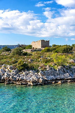 abandoned house ruin in the coast of Greece with turquoise sea water