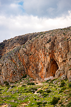 Cave of Elafonisos island with orange rock color painted in white, in Greece