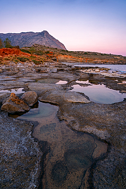 Aspes beach natural holes on the rocks full with water at sunset with turquoise water sea of Greece on the background