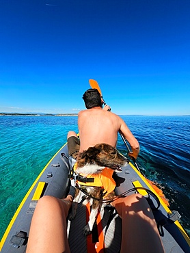 Man and dog on a kayak on the turquoise water sea of Greece