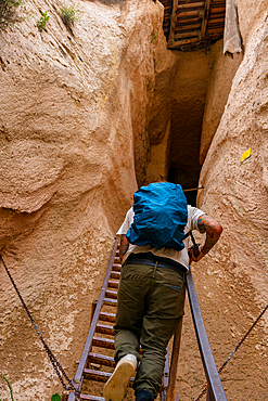 Man tourist climbing stairs of a cave built in the rock formations of Cappadocia, Turkey