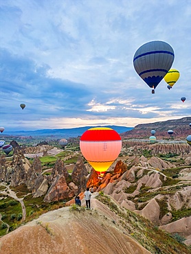Drone aerial view of tourists looking at hot air balloons flying over Cappadocia in Turkey at sunrise