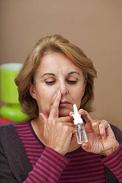 Elderly person using nose spray