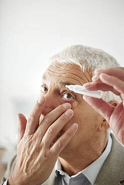 Elderly person using eye lotion