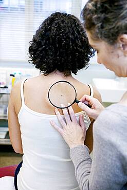 Dermatologist examining patient's moles.